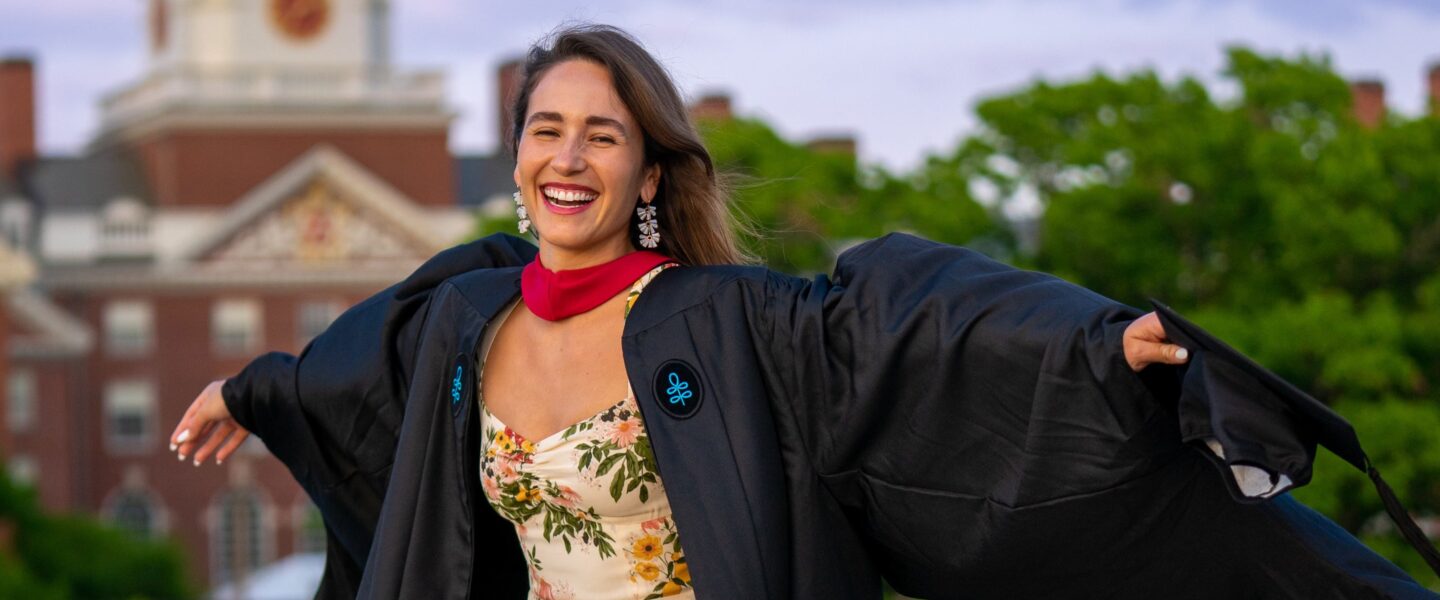 A woman smiling and spreading her arms wide in the wind