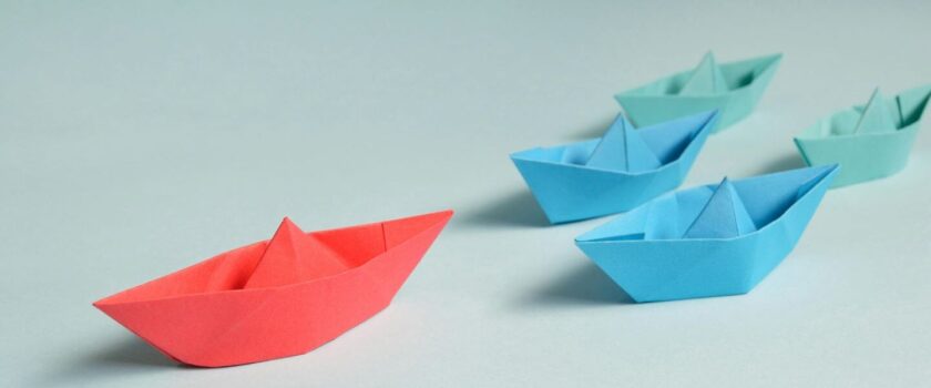 five paper boats on a neutral background
