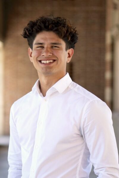 A man with brown hair and a white shirt smiling